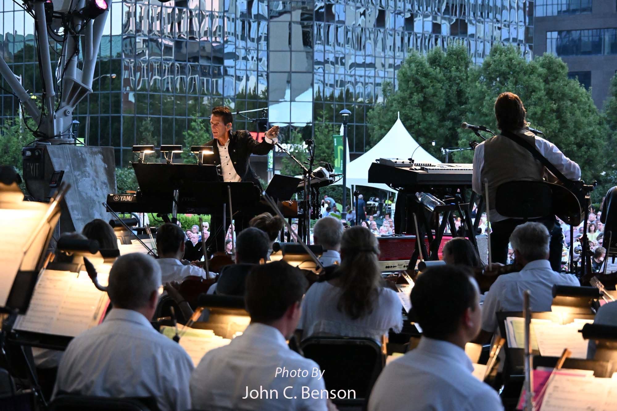 Tom Brooks conducting at dusk, the orchestra in the foreground