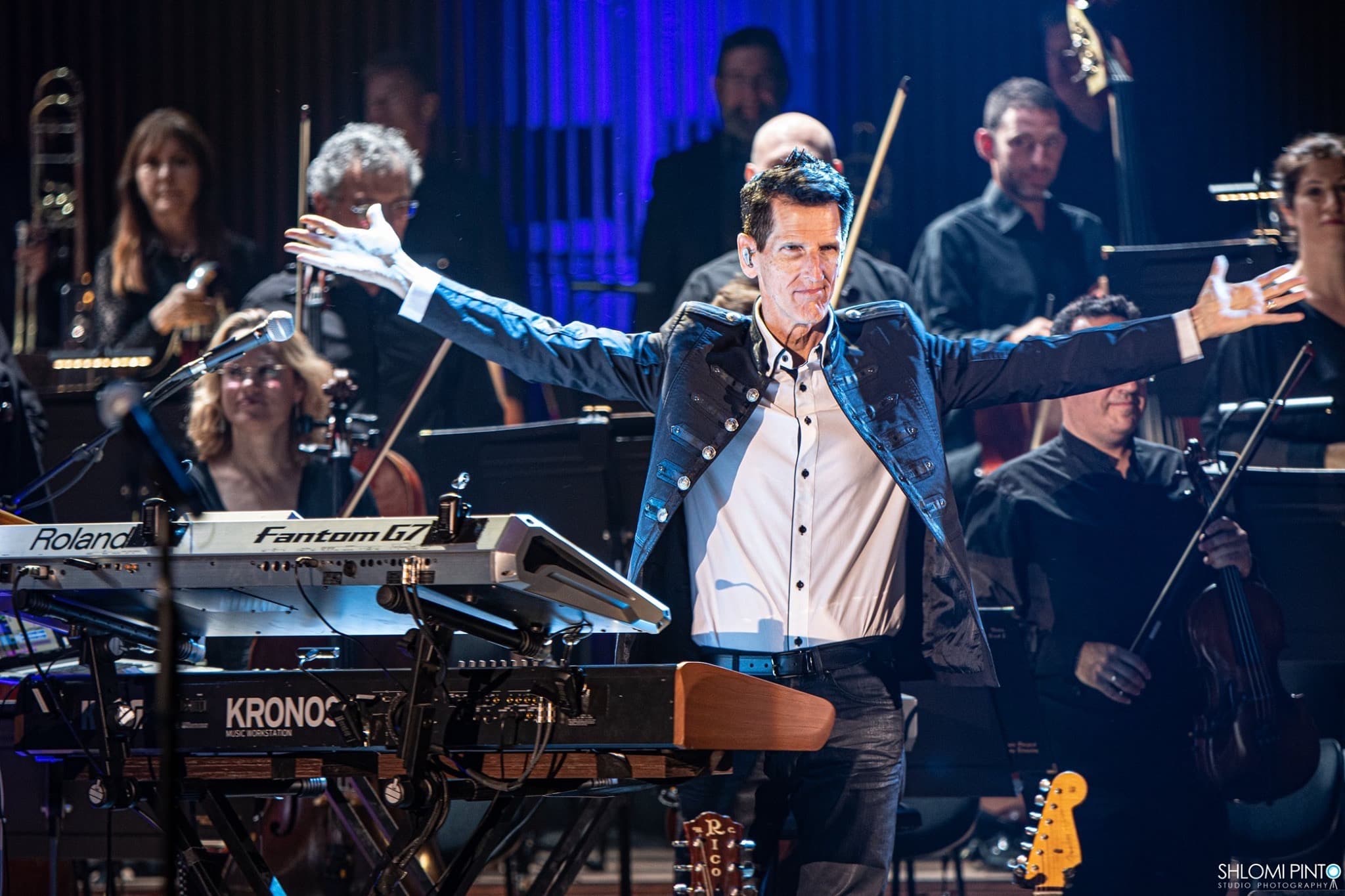 Tom Brooks with arms outstretched in front of the Israel Philharmonic